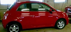 Kiiltäväksi käsitelty punainen Fiat 500 hallissa