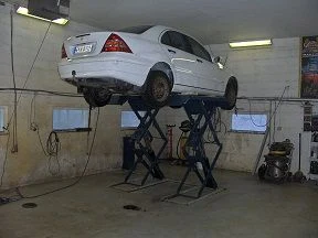 Valkoinen Mercedes-Benz saksinosturilla korjaamossa